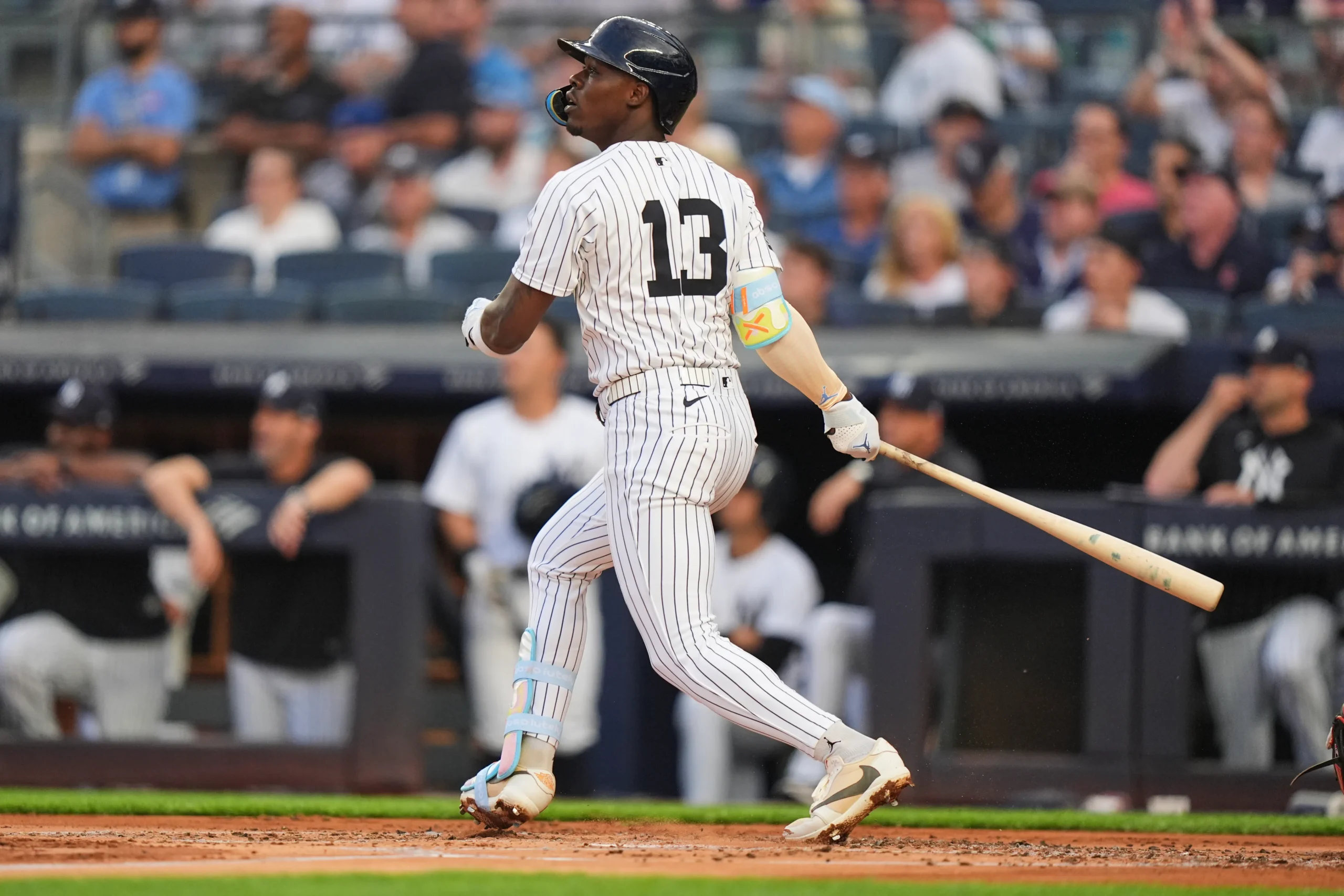 Jazz Chisholm Jr. watches the ball after a swing during a New York Yankees game, wearing the club’s pinstripe uniform with colorful protective gear and white cleats inside Yankee Stadium
