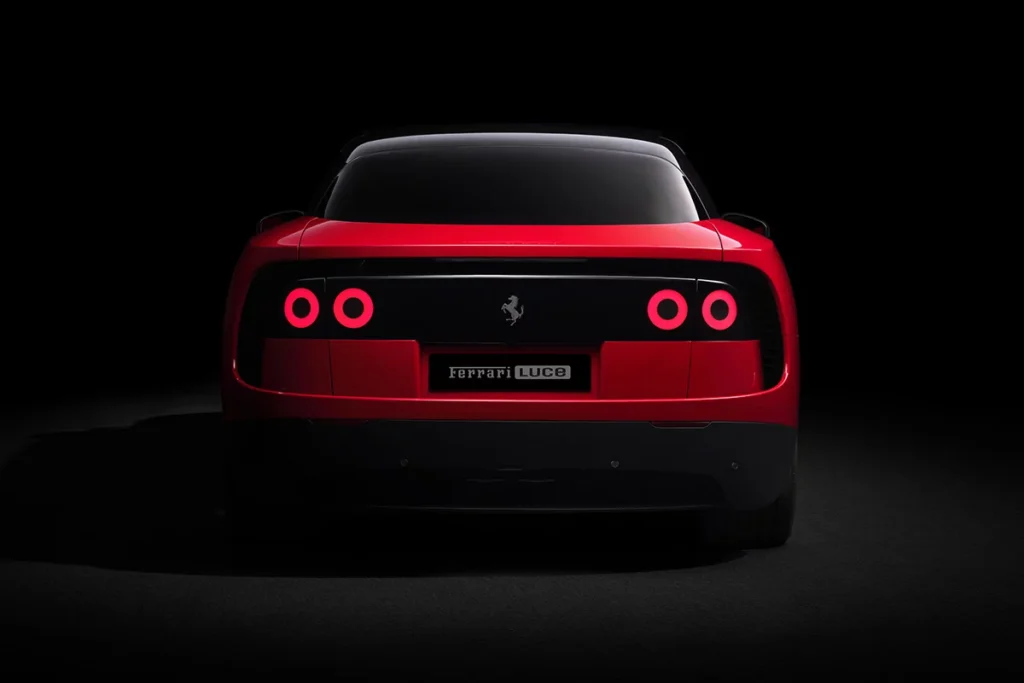 Studio rear view of a bright red futuristic electric grand tourer against a black background, featuring four illuminated circular LED taillights set within a seamless gloss-black rear panel, a minimalist tailgate design, dark lower diffuser detailing, and a wide planted stance beneath a smooth glass roofline