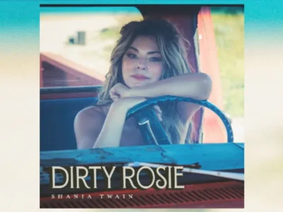 Cover artwork for “Dirty Rosie” featuring a woman leaning on the steering wheel inside a vintage vehicle, photographed in soft cinematic lighting with warm tones and the title “DIRTY ROSIE” and artist name displayed across the lower portion of the image