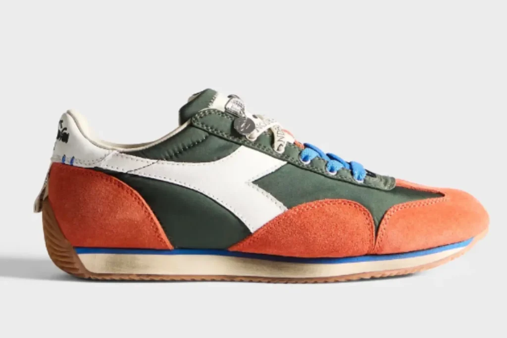 This JW Anderson x Diadora Equipe colorway combines deep navy nylon with mustard suede overlays, white leather side stripes, and soft pink laces for a playful reinterpretation of the archival runner. The slim silhouette and vintage-inspired sole preserve the Equipe’s 1975 athletic identity, while the bold color contrasts and premium Italian materials push it firmly into contemporary luxury sneaker territory