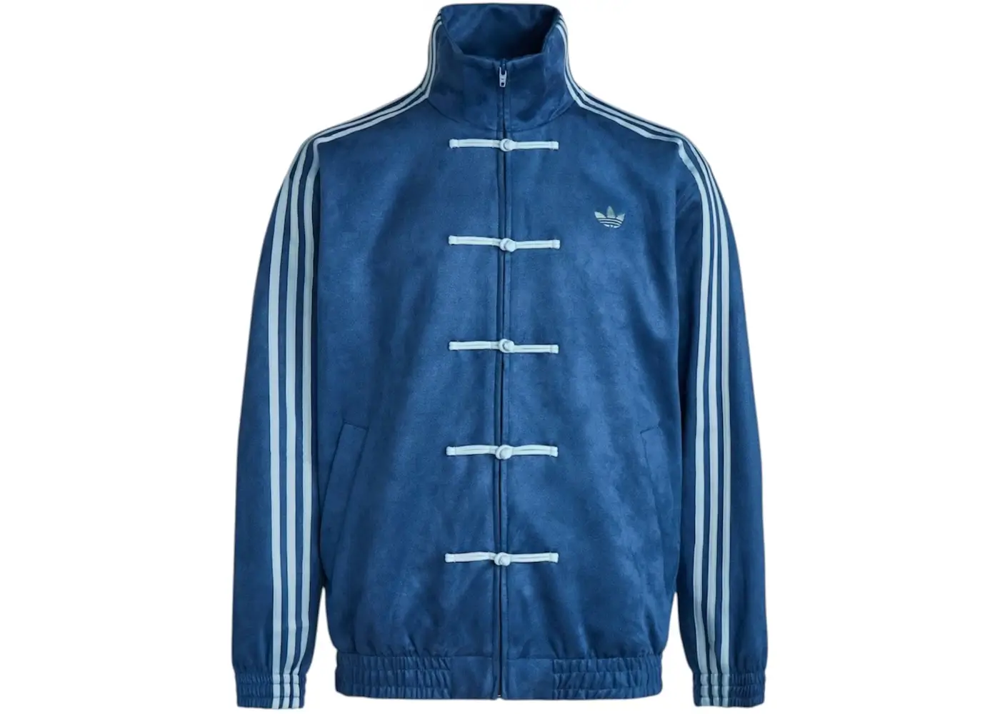 The adidas Originals CTT Chinese Track Top appears here in a rich deep-blue colorway, combining traditional Tangzhuang-inspired tailoring with classic adidas sportswear DNA. The silhouette features a high Mandarin-style collar, tonal pankou frog-button closures, and adidas’ signature Three Stripes running down the sleeves, creating a refined balance between heritage detailing and athletic structure. The suede-like texture and monochromatic finish give the jacket a more elevated, almost ceremonial feel while maintaining the relaxed proportions and everyday wearability associated with contemporary streetwear