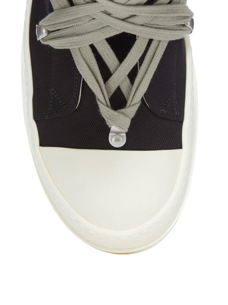 Close-up detail of the Rick Owens DRKSHDW Temple Megalace® shoe focusing on the oversized woven laces, metal lace hardware, textured black denim upper, and smooth off-white rubber toe cap