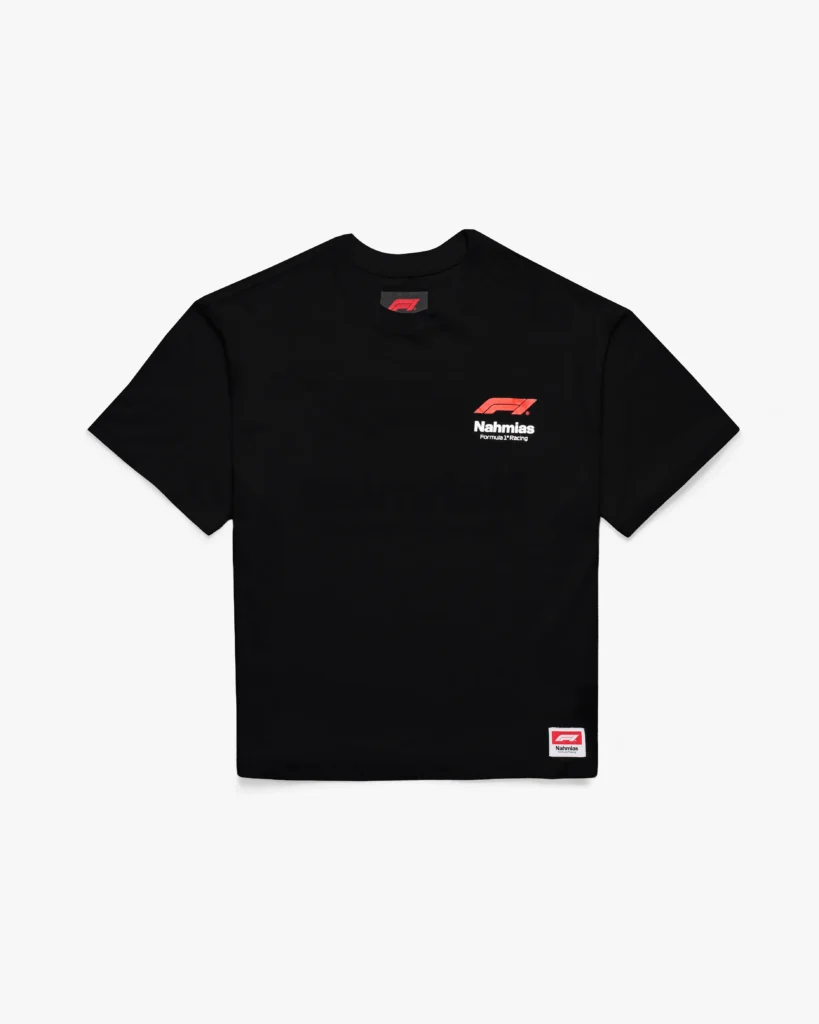 Black short-sleeve T-shirt with a clean, boxy silhouette and a classic crew neckline. The chest features a compact red Formula 1 logo paired with “Nahmias Formula 1® Racing” in white, positioned subtly on the left side. A woven branded patch at the lower hem echoes the same motif, adding a finishing detail. The minimalist design emphasizes contrast—deep black fabric against sharp red-and-white graphics—channeling a refined, motorsport-inspired aesthetic