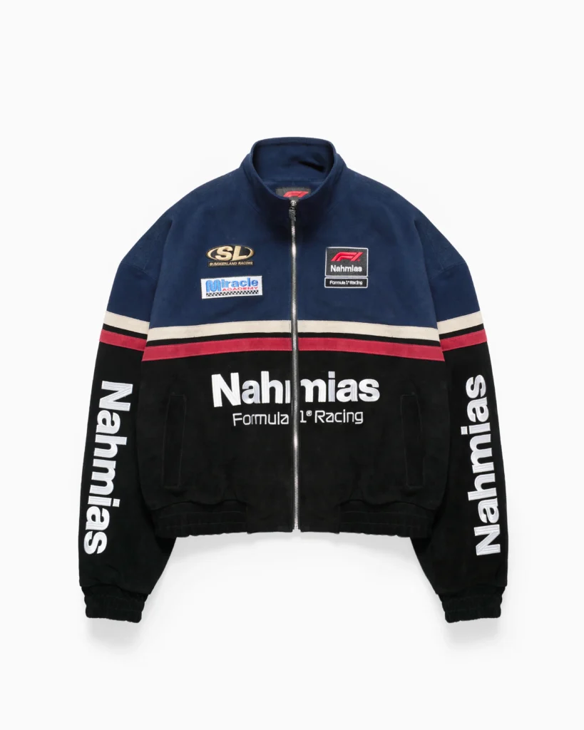 Navy and black zip-up racing jacket with a structured, slightly boxy silhouette and a stand collar. The design features bold horizontal striping across the chest in cream, red, and black, creating a classic motorsport color-block effect. The front is detailed with multiple sponsor-style patches, including “SL Summerland Racing,” a “Miracle Academy” graphic, and a Nahmias Formula 1® Racing badge, while large “Nahmias” lettering spans the lower front. Additional oversized “Nahmias” branding runs down both sleeves, reinforcing the race-team aesthetic. A full-length zipper, elasticated cuffs, and hem complete the piece, blending vintage racing influence with elevated streetwear execution