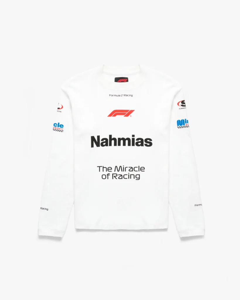 White long-sleeve thermal top with a textured waffle-knit construction and a clean, slightly fitted silhouette. The front features a centered red Formula 1 logo above bold black “Nahmias” lettering, followed by “The Miracle of Racing” in a refined, understated type. Additional motorsport-inspired graphics appear across the sleeves, including sponsor-style patches and subtle “Formula 1® Racing” text details. The crisp white base amplifies the contrast of the red and black branding, giving the piece a sharp, race-inspired identity with a streamlined, contemporary feel