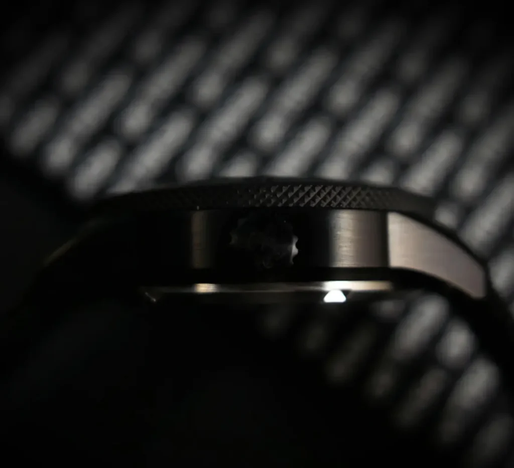 Macro side-profile detail of the Detrash Gotham’s Vigilante 2 watch case in a low-light setting, highlighting the stealth-black brushed finish, textured rotating bezel edge, and subtle crown integration. The shallow depth of field and shadow-heavy composition emphasize the watch’s Batman-inspired dark aesthetic and industrial precision
