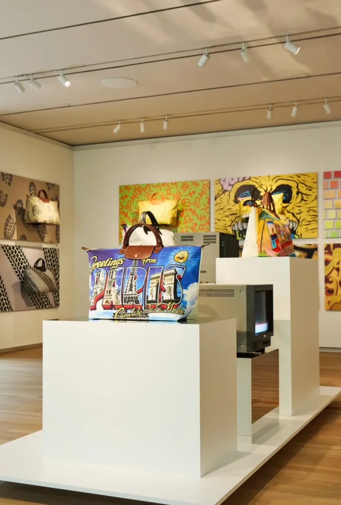 The “Greetings from Paris” Longchamp Le Pliage bag sits on display amid archival artworks celebrating Jeremy Scott’s imaginative reinterpretations of the iconic tote