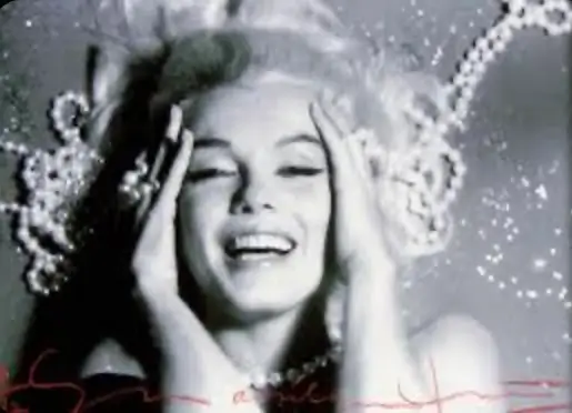 Black-and-white close-up portrait of Marilyn Monroe smiling brightly while framed by cascading strands of pearls during Bert Stern’s legendary 1962 Last Sitting photo session. Soft lighting and sparkling reflections create an intimate, dreamlike atmosphere around her expressive face and platinum blonde hair