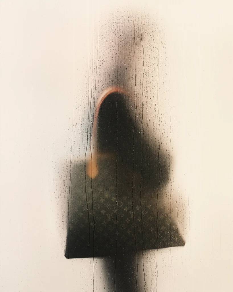 Model wearing a cream textured zip-up jacket with dark indigo denim and a black Louis Vuitton tote bag