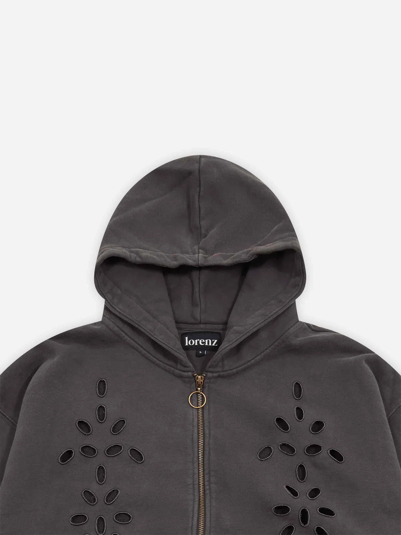 Close-up of the Lorenz Studio Broderie Hoodie in washed black highlighting floral-inspired cutwork embroidery, oversized hood construction, vintage-faded cotton texture, and antique brass zip closure