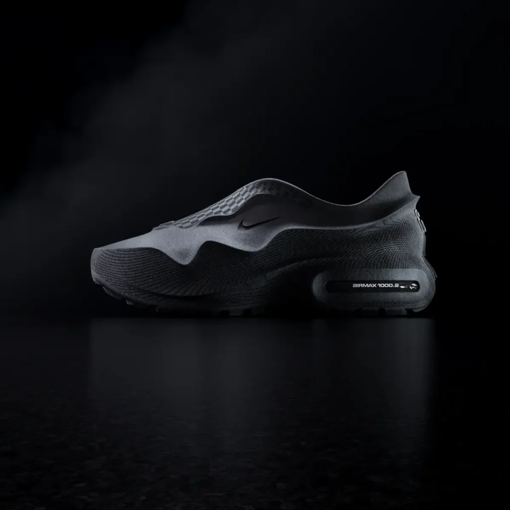 Side profile of an all-black Nike Air Max 1000.2 futuristic slip-on shoe with sculpted textured tooling and visible Air cushioning in a dark studio setting