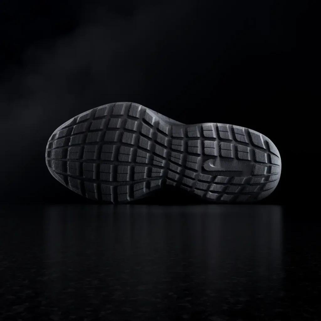 Bottom outsole view of the all-black Nike Air Max 1000.2 featuring segmented geometric traction pods and tonal Nike branding in a dark studio environment