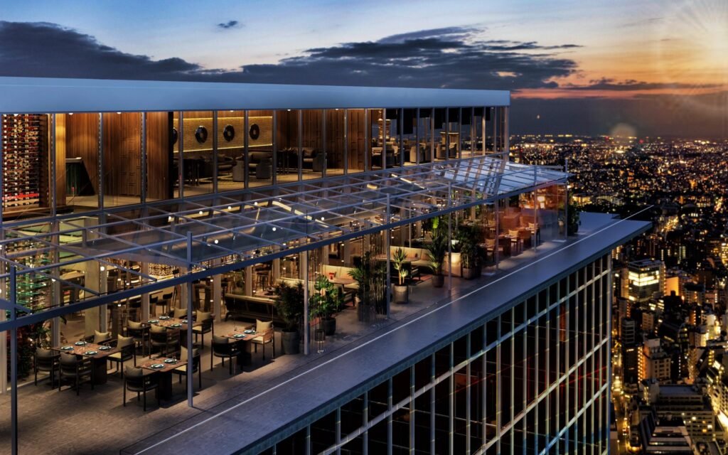 A rooftop venue glows above the city skyline at dusk, featuring expansive glass architecture, warm interior lighting, outdoor dining terraces, and panoramic urban views stretching across the illuminated nightscape. The elevated atmosphere blends modern hospitality design with cinematic metropolitan energy, evoking the aspirational mood associated with contemporary fashion events and exclusive rooftop experiences