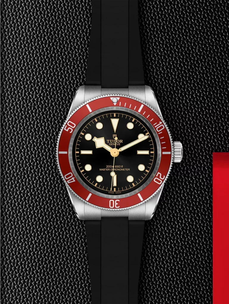TUDOR Black Bay 41mm dive watch with burgundy bezel and black dial on a black rubber strap, set against a textured black background with a red accent, highlighting its sporty, modern aesthetic