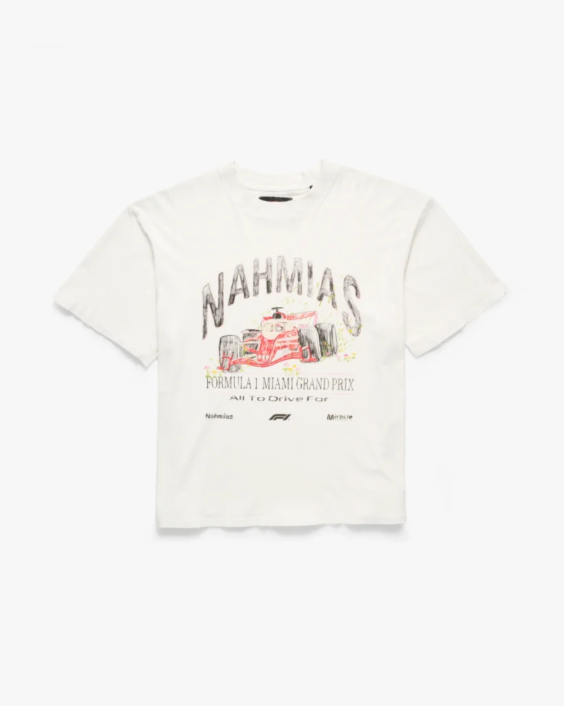 Off-white short-sleeve T-shirt with a relaxed, slightly vintage-inspired fit and a soft, worn-in finish. The front features a hand-drawn style graphic of a Formula 1 car, rendered in sketch-like lines with red highlights, beneath arched “NAHMIAS” lettering. Below, “Formula 1 Miami Grand Prix” and “All To Drive For” text adds a commemorative feel, accompanied by small co-branded marks including Nahmias and F1 logos. The overall design leans into a nostalgic, illustrated aesthetic, blending motorsport energy with an artful, collectible streetwear approach