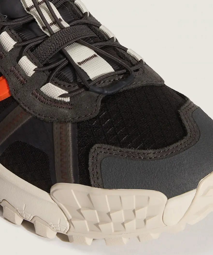 Close-up detail of the Vans MTE Travel Pack shoe highlighting the textured black mesh toe box, reinforced rubber mudguard, technical lace system with webbing loops, layered suede overlays, and rugged off-white trail outsole construction