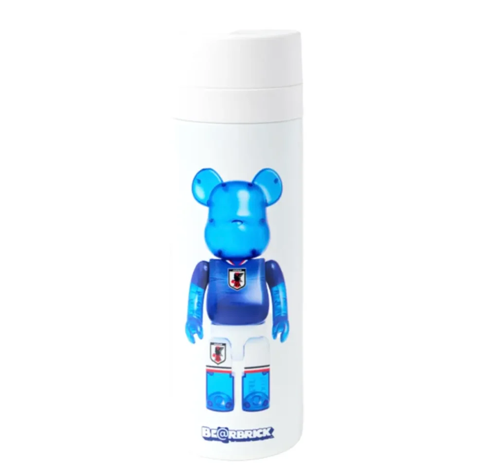 Official BE@RBRICK × Japan National Soccer Team (SAMURAI BLUE) insulated tumbler in matte white featuring a full-length translucent blue BE@RBRICK character wearing Japan’s national football kit with JFA crest detailing and connective branding near the base