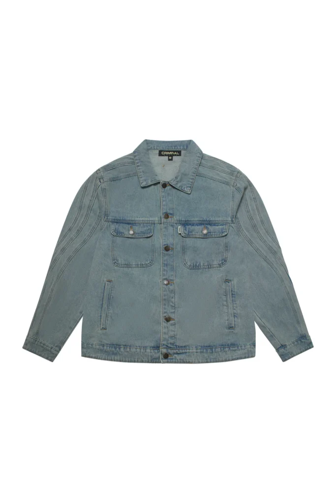 Light-wash denim jacket with exaggerated wavy seam paneling along the sleeves, featuring dual flap chest pockets, vertical side pockets, and a relaxed workwear-inspired silhouette. The faded blue wash and curved construction lines give the classic trucker jacket a sculptural, contemporary streetwear feel