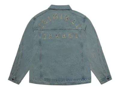Rear view of a light-wash denim jacket featuring oversized embroidered “CRIMINAL DAMAGE” branding across the back yoke. The faded indigo finish, clean panel construction, and relaxed silhouette blend vintage Americana denim references with modern streetwear identity and bold graphic detailing