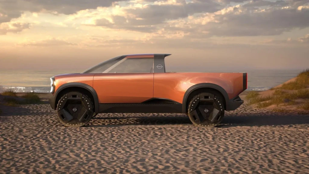 Full side profile of the Nissan Surf-Out Concept on a beach landscape, emphasizing its long cargo bed, elevated ride height, floating roof effect, and rugged electric adventure-truck stance