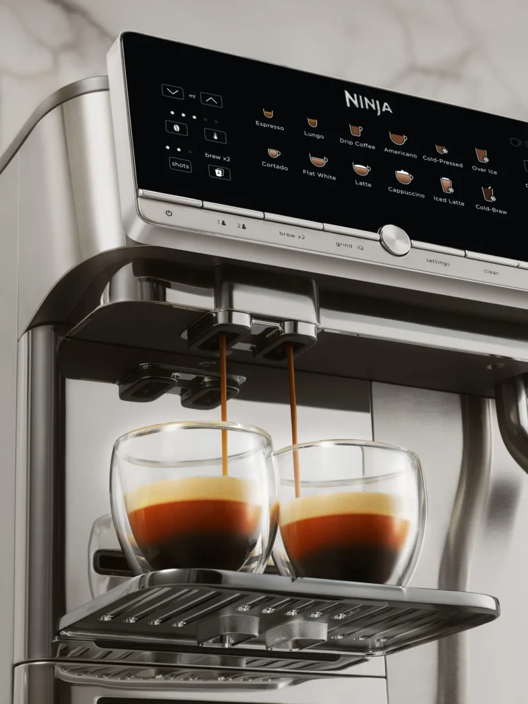Close-up of the Ninja AutoBarista Pro touchscreen control panel showing multiple coffee presets while extracting fresh espresso into double-wall glass cups with rich crema