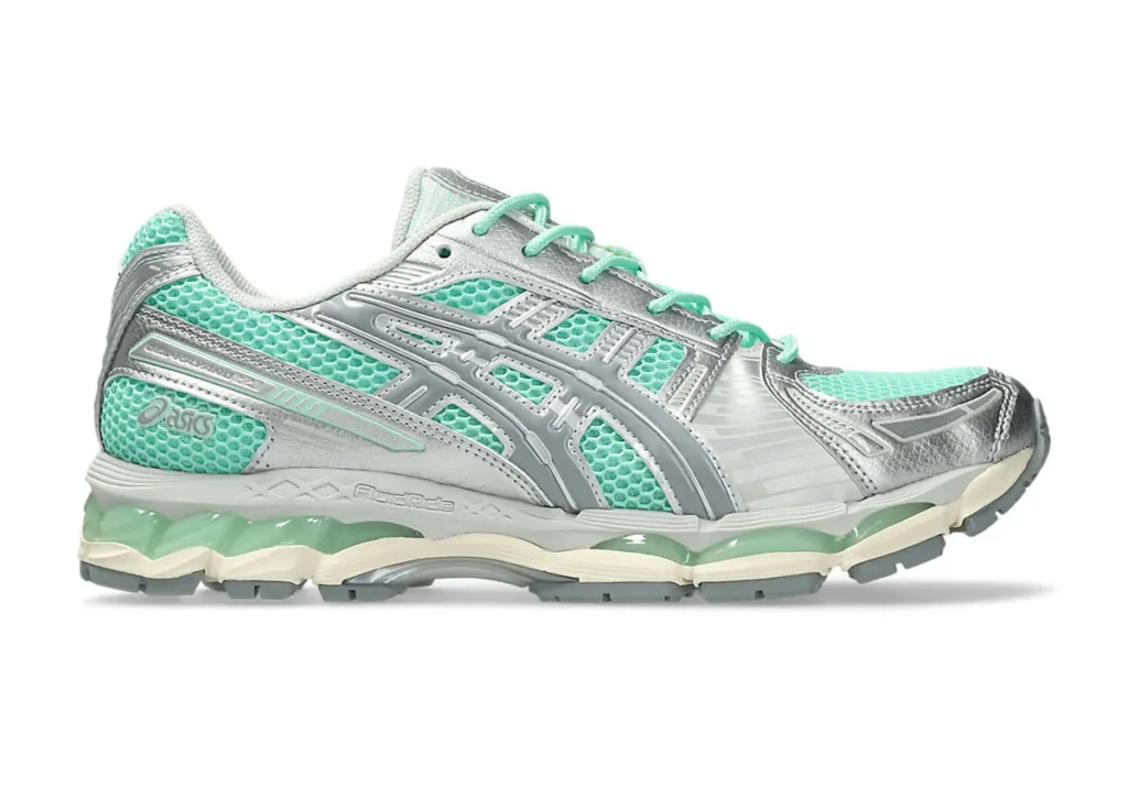 Side profile of the ASICS GEL-Kayano 12.1 sneaker in Ice Green and Gravel with honeycomb mesh texture, oversized ASICS stripe overlays, FluidRide midsole branding, and visible cushioning windows