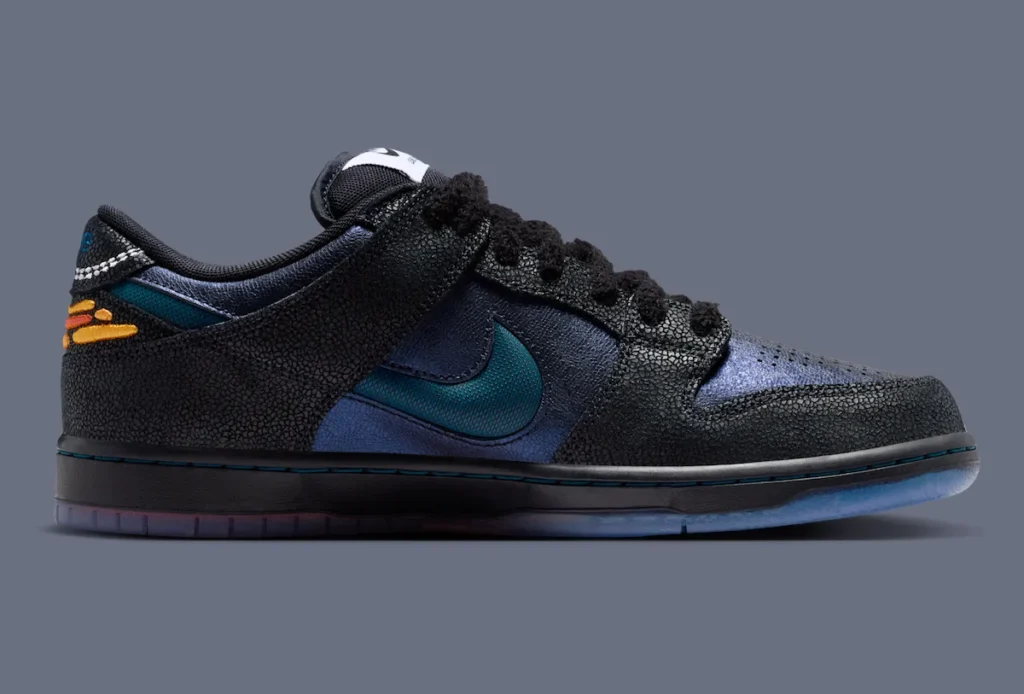 Medial side view of the Bluetile x Nike SB Dunk Low “Monarch Butterfly” featuring textured black overlays, shimmering navy leather panels, fuzzy black laces, a deep blue textured Swoosh, and orange butterfly wing-inspired embroidery wrapping the heel