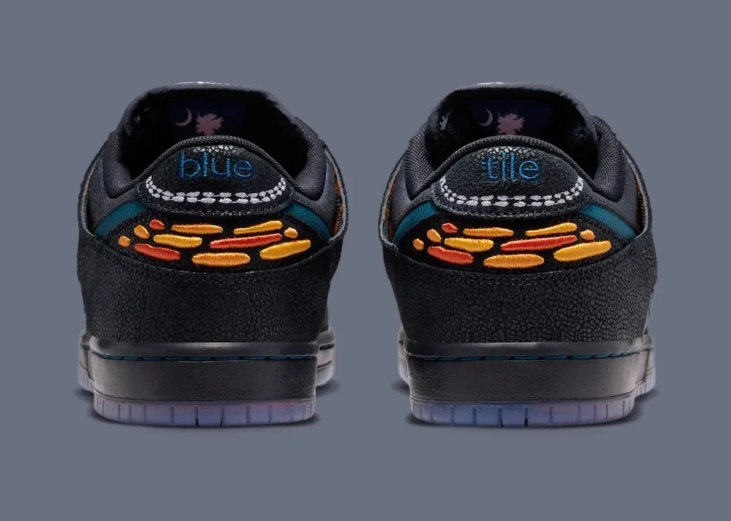 Rear heel view of the Bluetile x Nike SB Dunk Low “Monarch Butterfly” featuring embroidered orange monarch wing-inspired graphics, textured black overlays, translucent outsoles, and split “blue” and “tile” embroidery branding across the heel tabs