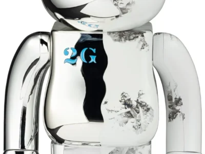 Chrome and translucent BE@RBRICK collectible figure featuring mirrored silver surfaces, frosted clear sections, blue eye detailing, and abstract monochrome artwork across the body
