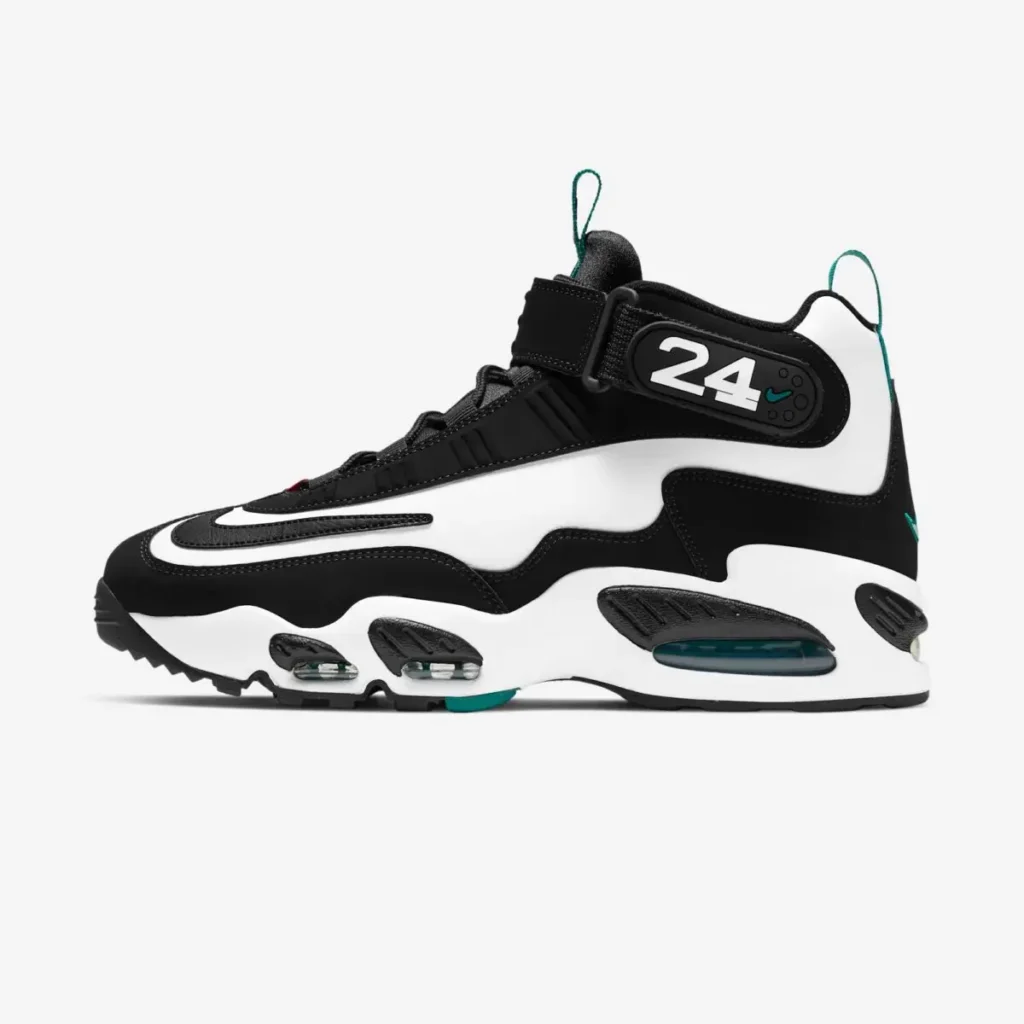 Side profile of a black-and-white Nike Griffey-style shoe featuring oversized wavy paneling, a large outlined Swoosh wrapping around the upper, and visible teal-tinted Air cushioning units embedded in the midsole. The high-top silhouette includes a velcro ankle strap marked with the number “24,” referencing Ken Griffey Jr., alongside subtle teal accents on the heel, pull tabs, outsole, and mini logo detailing. The shoe is photographed against a clean light gray studio background