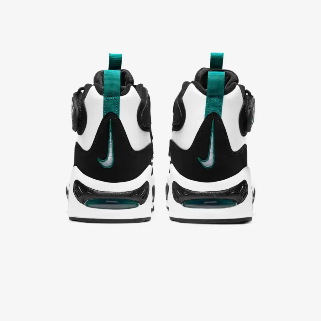 Rear view of a pair of black-and-white Nike Griffey-inspired high-top shoe featuring teal heel pull tabs, embroidered mini Swooshes outlined in teal, and chunky white midsoles with visible teal-tinted Air cushioning windows at the heel. The layered black-and-white panel construction emphasizes the silhouette’s bold retro baseball design language, while the symmetrical studio presentation sits against a clean light gray background