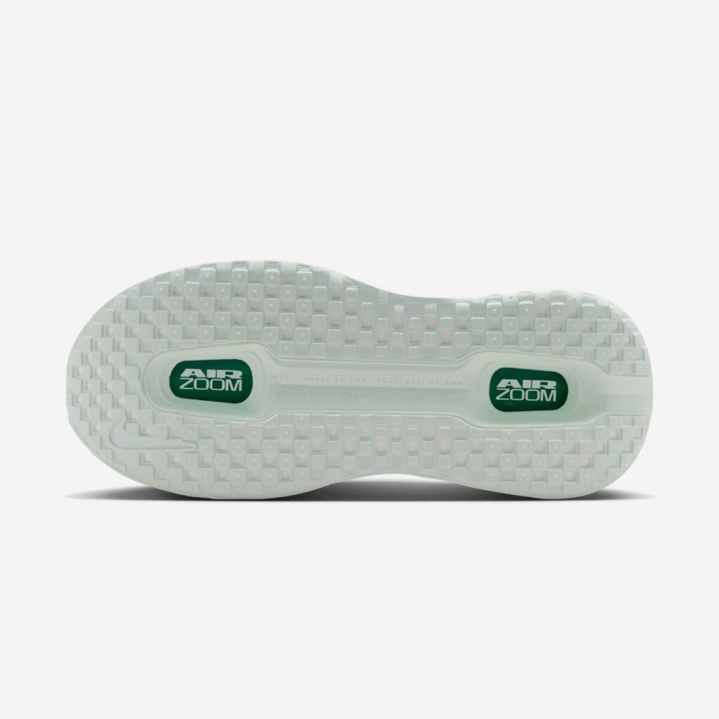 Outsole view of the Nike Vomero Premium Women’s “Barely Green” (HM5973-300), featuring a translucent pale green rubber tread with a grid-like traction pattern and dual visible Air Zoom units in the forefoot and heel, highlighted with deep green branding accents