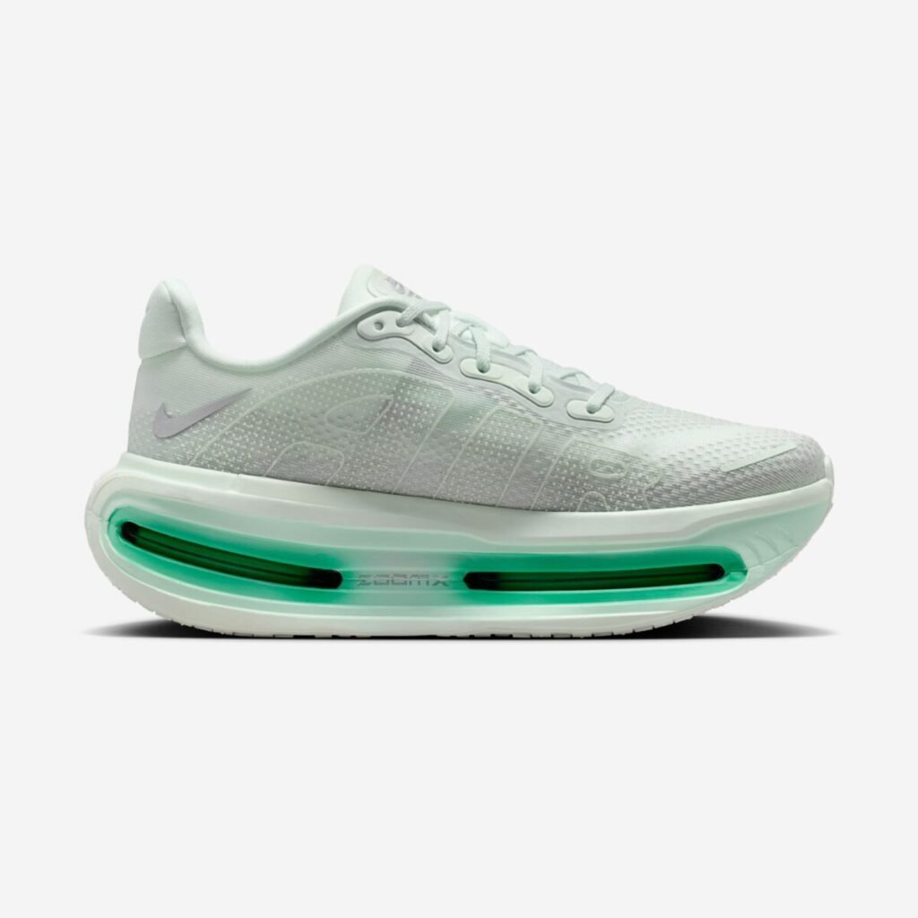 Angled lateral view of the Nike Vomero Premium Women’s “Barely Green” (HM5973-300), highlighting the soft green engineered mesh upper with subtle textural overlays, metallic silver Swoosh at the heel, and a sculpted high-stack midsole featuring full-length, green-tinted Air Zoom cushioning for a plush, elevated ride