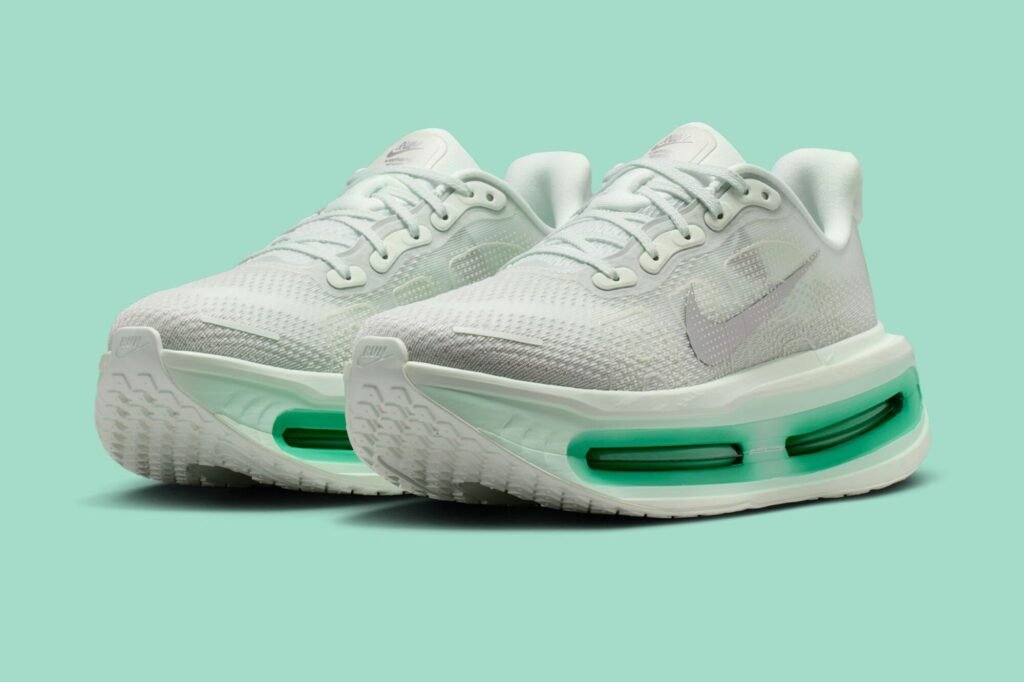 Angled pair shot of the Nike Vomero Premium Women’s “Barely Green” (HM5973-300), showcasing the soft pastel green engineered mesh uppers, metallic silver Swooshes, and the sculpted high-stack midsoles with glowing green-tinted Air Zoom cushioning, set against a matching mint backdrop for a clean, spring-forward presentation