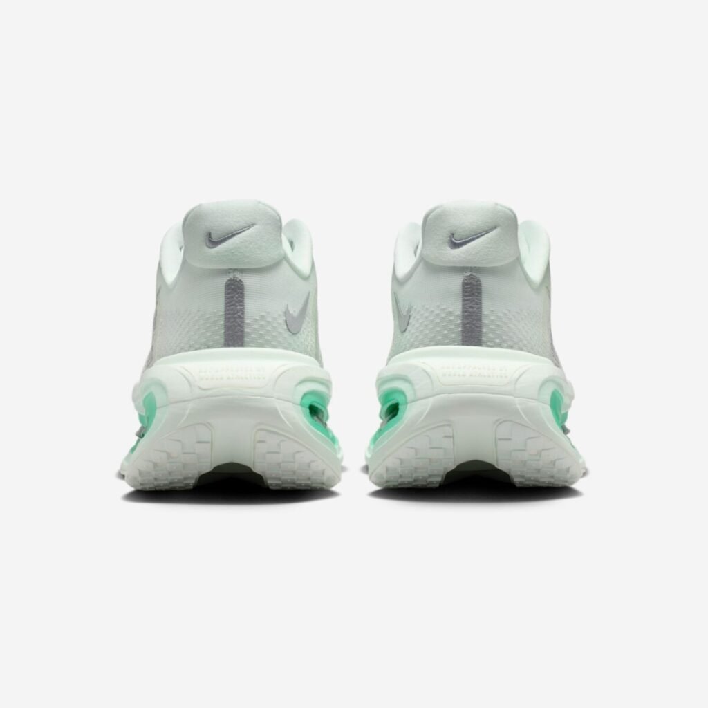 Rear view of the Nike Vomero Premium Women’s “Barely Green” (HM5973-300), highlighting the padded heel collars with embroidered mini Swooshes, a vertical reflective pull tab detail, and the sculpted midsole with exposed green-tinted Air Zoom units visible at the heel for added cushioning and visual depth
