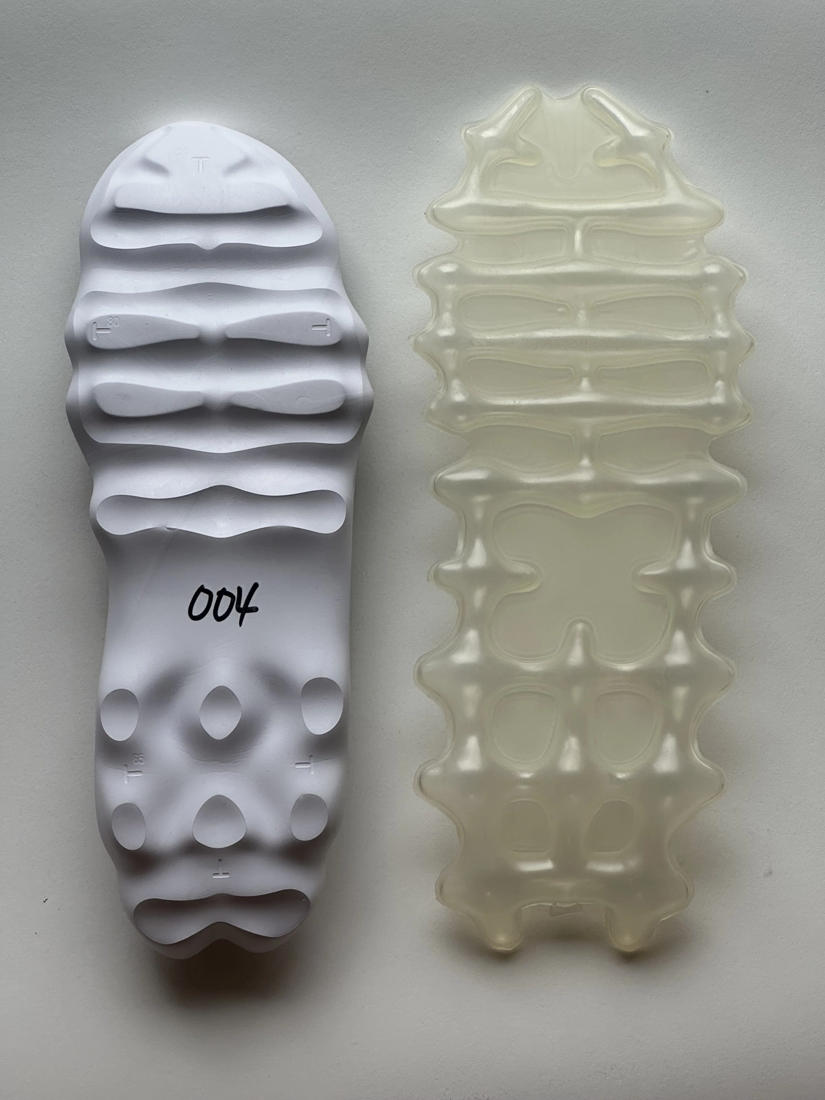 Prototype comparison of Nike’s Air Liquid Max system, pairing a sculpted white outsole mold with the translucent full-length Air unit to highlight the intricate internal cut-outs and pressure-mapped cushioning geometry behind the silhouette’s fluid ride