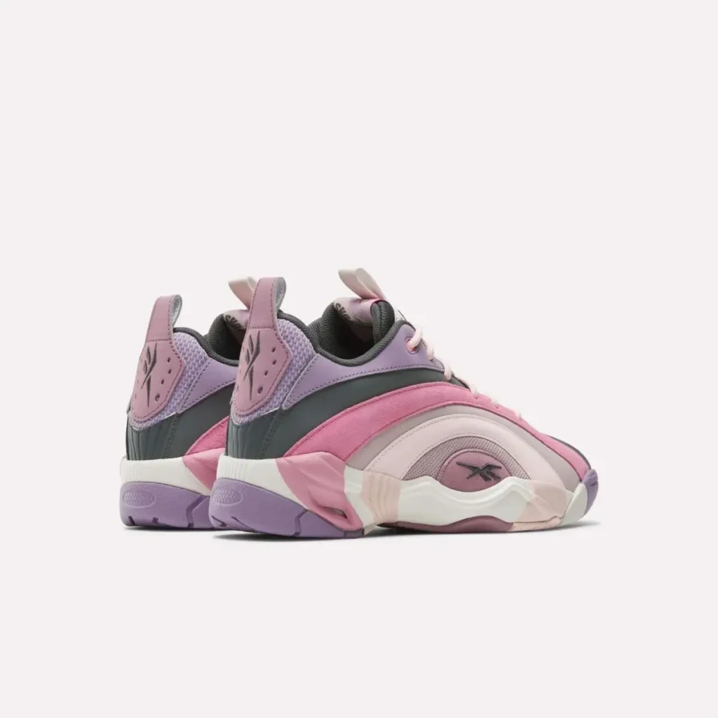Rear angled view of pastel Reebok basketball sneakers featuring pink suede overlays, lavender mesh panels, charcoal accents, and sculpted cream midsoles with chunky retro tooling