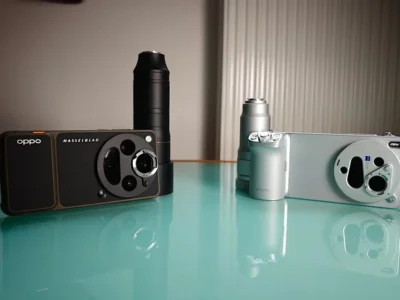 Side-by-side comparison of the Oppo Find X9 Ultra and Vivo X300 Ultra on a glossy reflective surface, showcasing their oversized circular camera systems and attached telephoto accessories. The Oppo model appears in a dark finish with Hasselblad branding, while the Vivo version appears in silver with ZEISS-inspired modular photography style