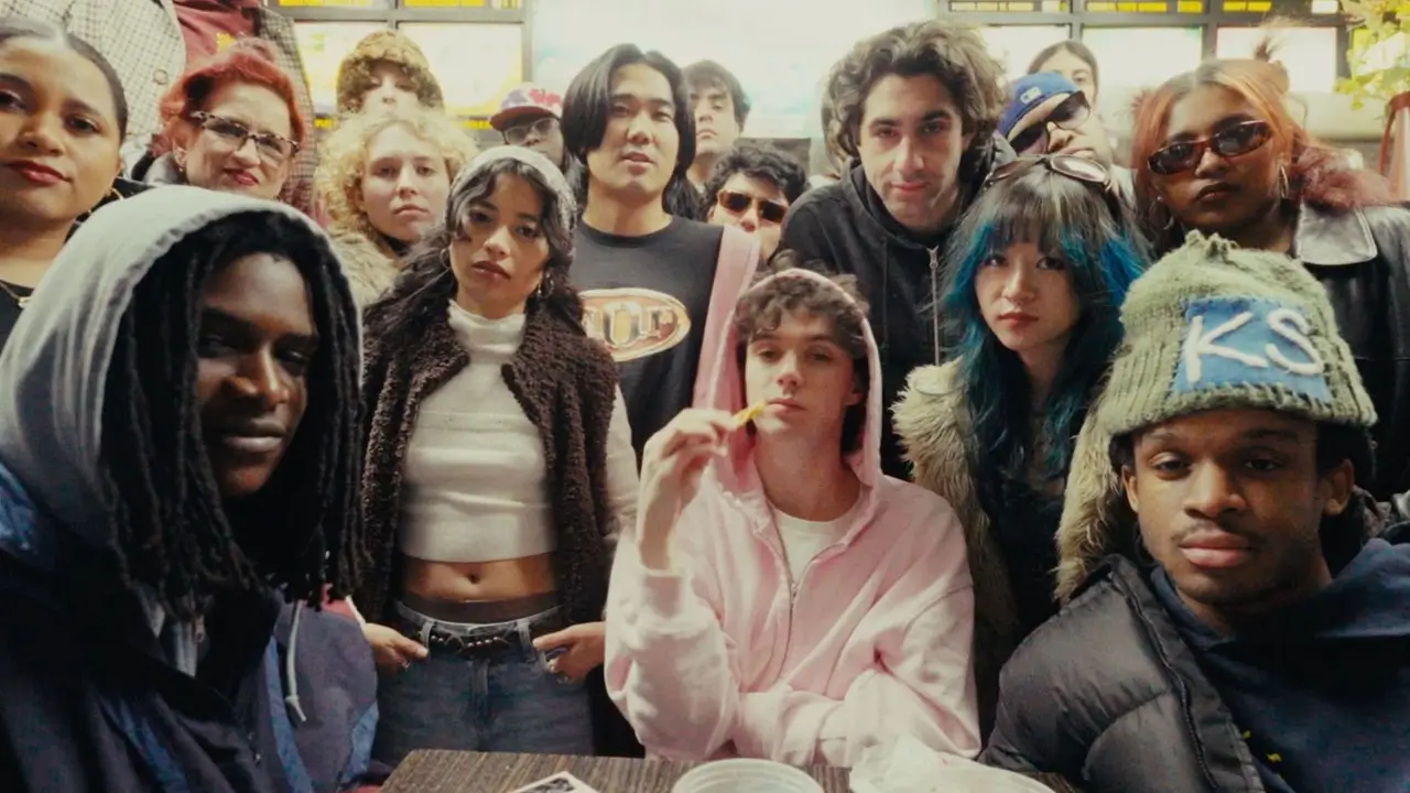 WHATMORE posing with friends and supporters inside a late-night diner, capturing the collective’s youthful New York creative energy through layered streetwear and candid group chemistry