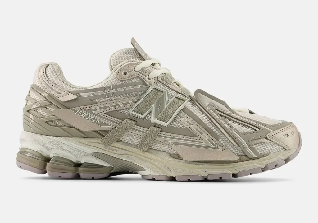 Angled profile of the New Balance 1906A “Arid Stone” highlighting its layered mesh construction, exaggerated deconstructed overlays, extended N-Lock detailing, and visible N-ERGY cushioning in soft earth-toned neutrals