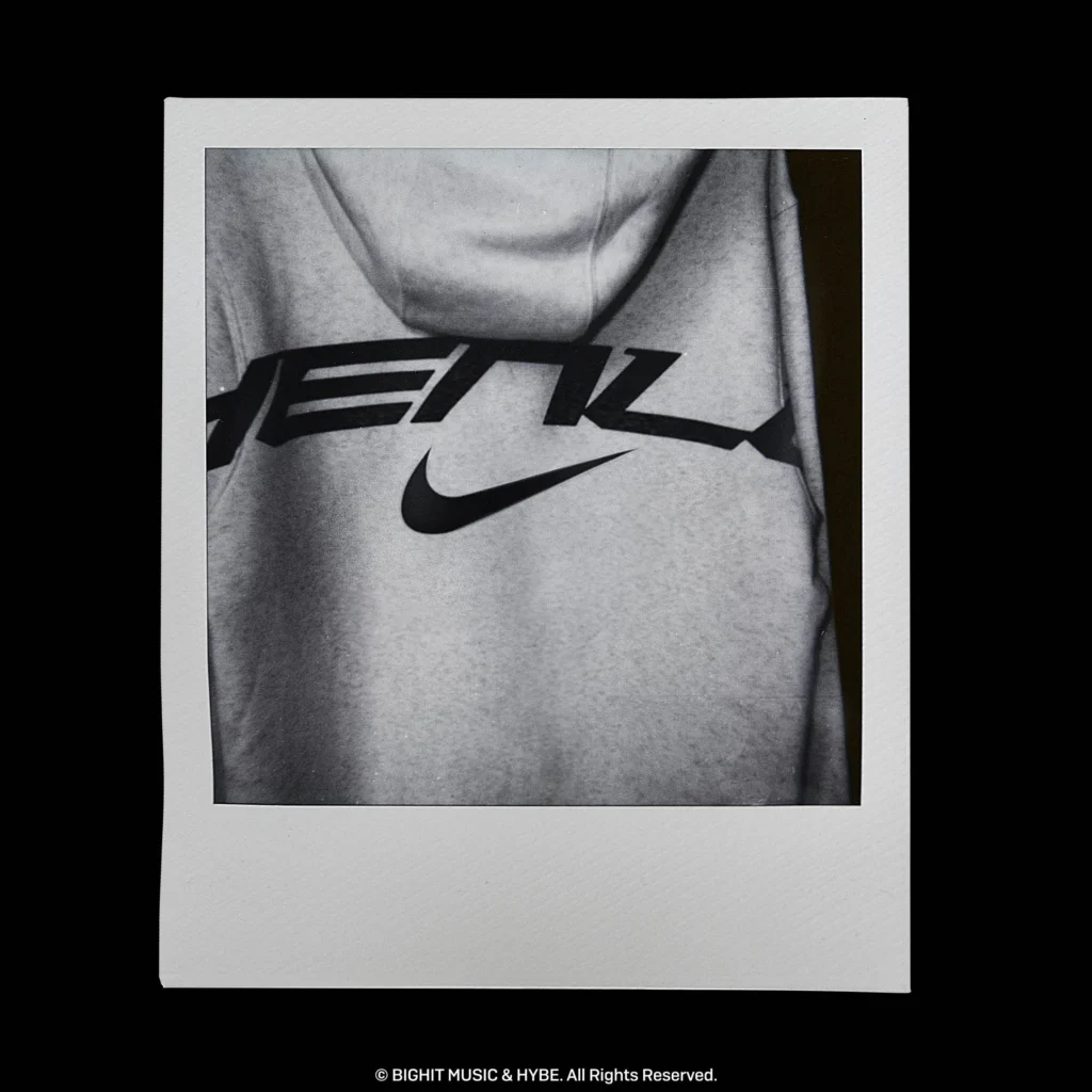 Close-up of a light-colored Nike BTS hoodie featuring large stylized BTS lettering and a centered Nike Swoosh logo