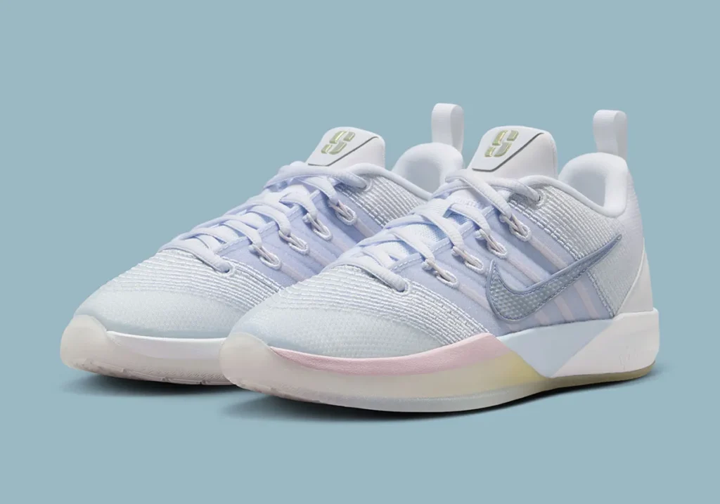Three-quarter front view of the Nike Sabrina 3 “Football Grey / Royal Pulse,” showing the pair angled side-by-side with a soft white and light grey engineered mesh upper accented by pastel blue and lilac tones through the midfoot bands. A textured metallic Swoosh stands out along the lateral side, while the midsole transitions into a subtle gradient of pink, yellow, and icy blue near the forefoot. The tongues feature gold Sabrina logos, and the translucent outsole adds a faint yellow tint, all set against a muted blue studio background