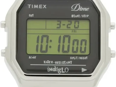 Front-facing product image of the Dime x Timex T80 Presented by END. featuring a polished silver-tone case, retro LCD display, and pyramid-studded stainless steel bracelet inspired by punk and skate culture