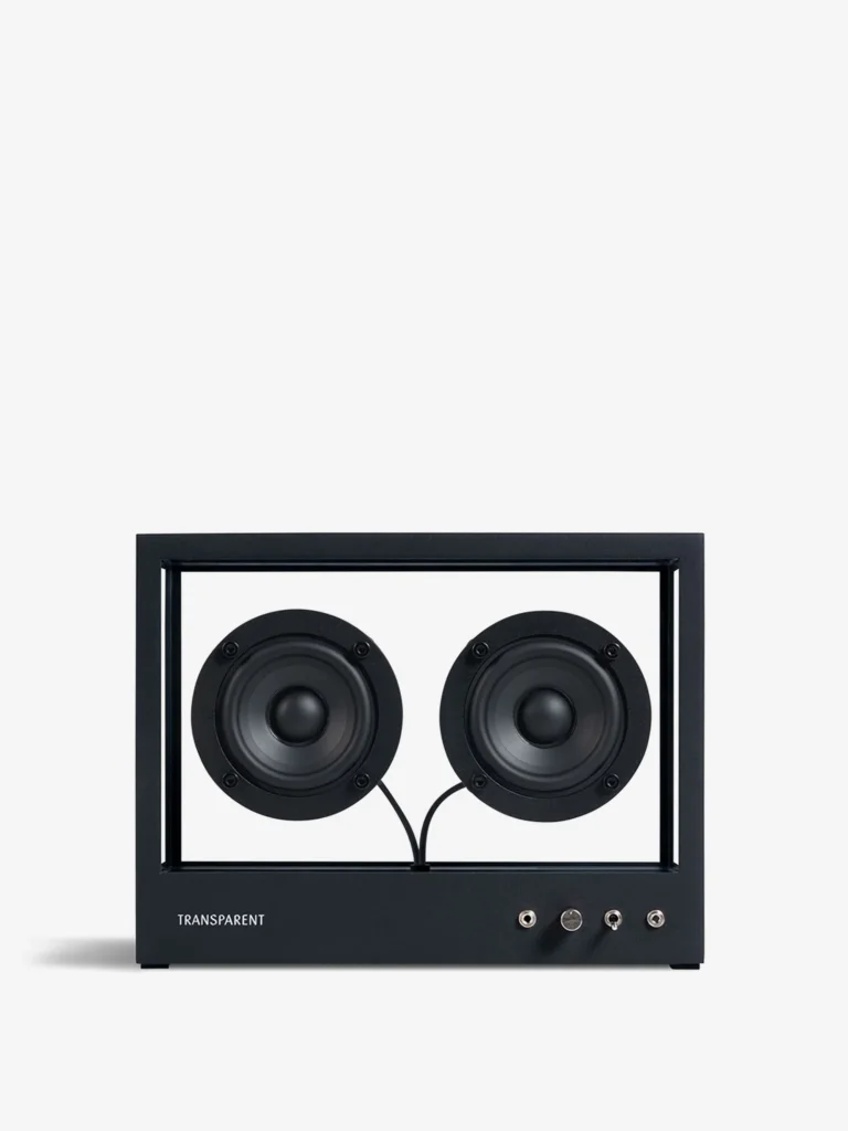 Front-facing view of the Transparent Sound Small Speaker in Black featuring dual exposed circular drivers, minimalist black aluminum framing, visible cabling, and industrial Scandinavian design against a clean gray background