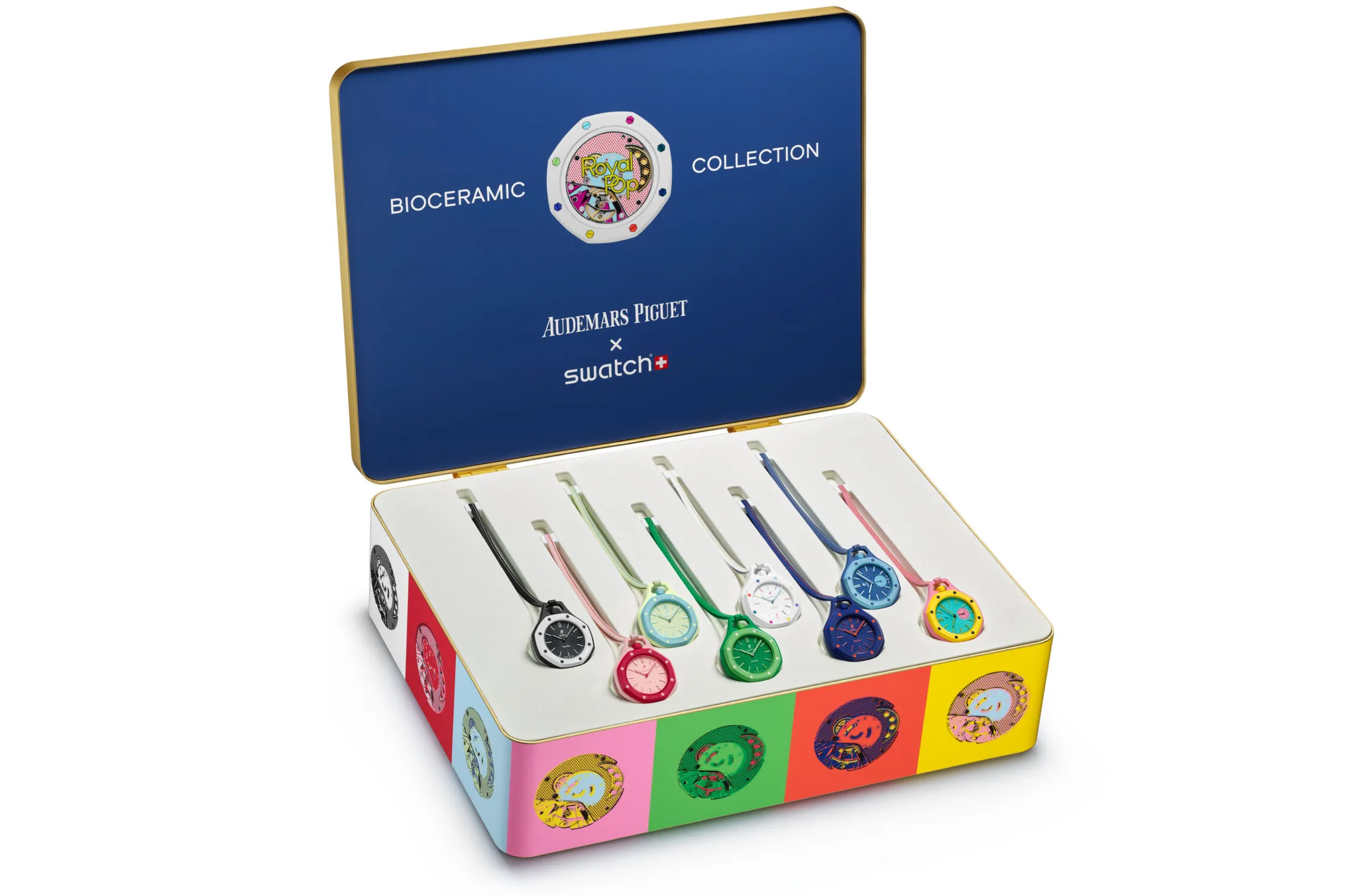 A studio product shot of a colorful presentation case housing eight pendant-style bioceramic watches from the fictional Audemars Piguet x Swatch “Royal Pop” collection, displayed inside a blue-lined collector’s box accented with vibrant pop-art graphics and multicolored watch variants
