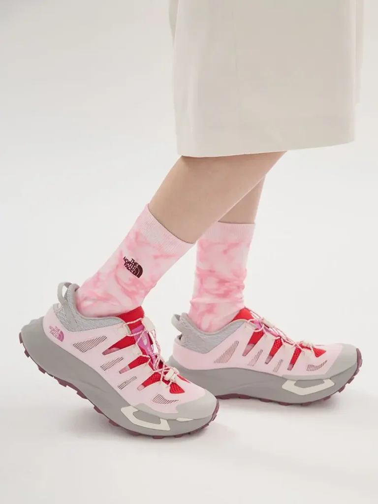 Lifestyle side view of The North Face VECTIV Breeze trail shoes paired with pink logo socks, blending hiking functionality with day fashion