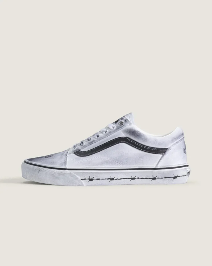 Side profile of the white Travis Barker x Vans Old Skool featuring distressed treatment, black side stripe, and barbed-wire graphic along the mid