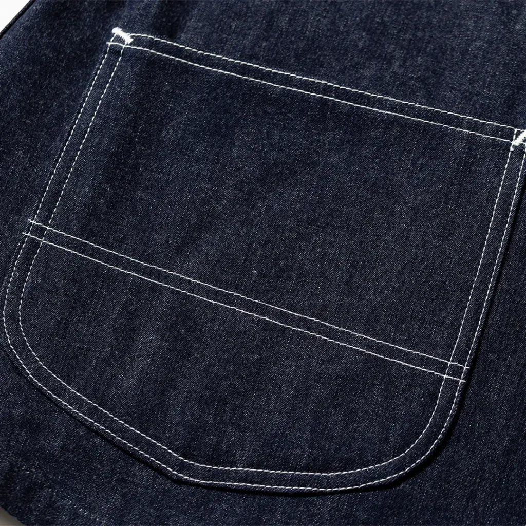 Close-up of the oversized rear utility pocket on the Lee 11-W denim trousers, highlighting curved corners, reinforced white stitching, and heavyweight raw denim fabric
