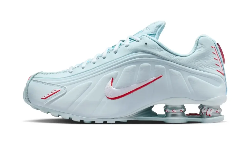 Side profile of the Nike Shox R4 Light Aqua showcasing sculpted paneling, a white-and-red Swoosh, and the iconic Shox heel cushioning system