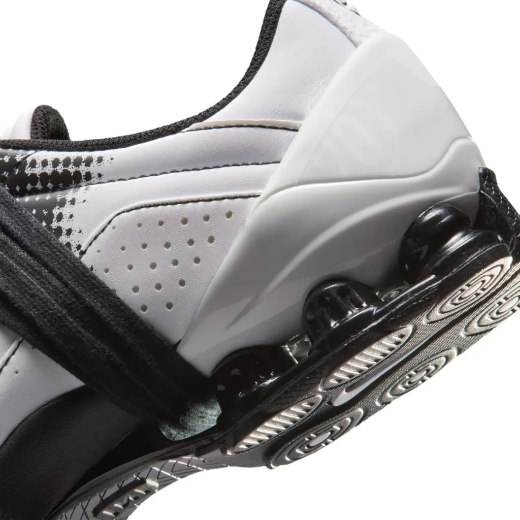 Detailed heel close-up of the white colorway highlighting perforated side panels, sculpted heel structure, and black Shox cushioning pod